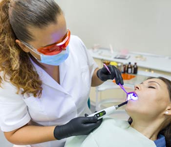 Adult female dentist treating patient woman teeth.